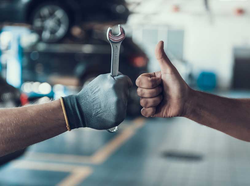 man holding wrench and giving man thumbs up