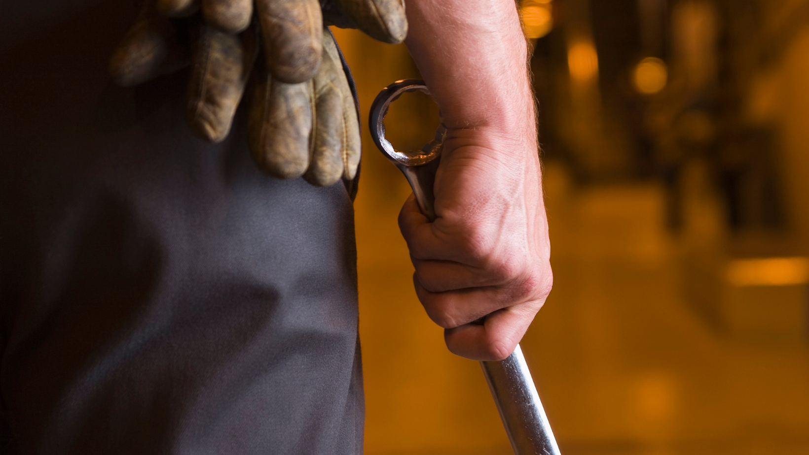 mechanic with gloves in pocket holding wrench