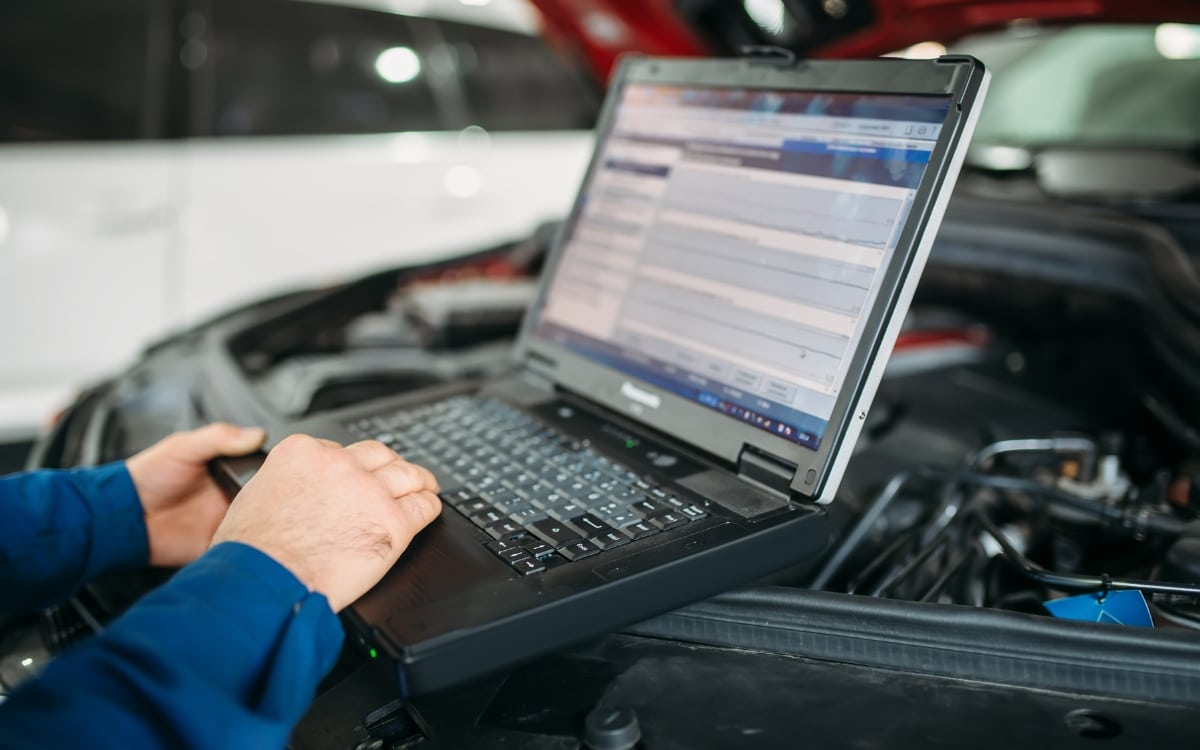 Auto tech using computer to test vehicle